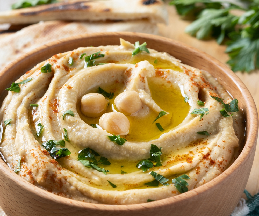 Smooth and creamy classic hummus in a bowl with pita